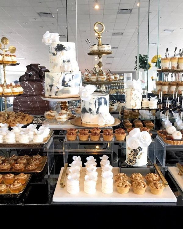 Mesa de postres amplia con pastel de pisos y variedad de formatos en salón corporativo