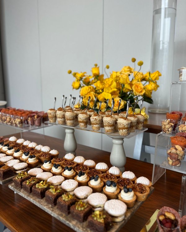 Mesa de postres con flores rosadas y variedad de canutos individuales