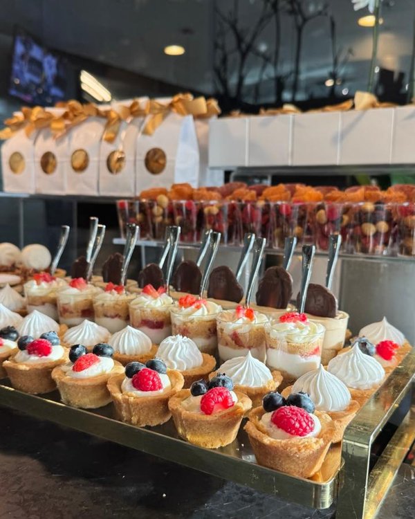 Mostachones individuales con frutos rojos en bandeja dorada para mesa de postres