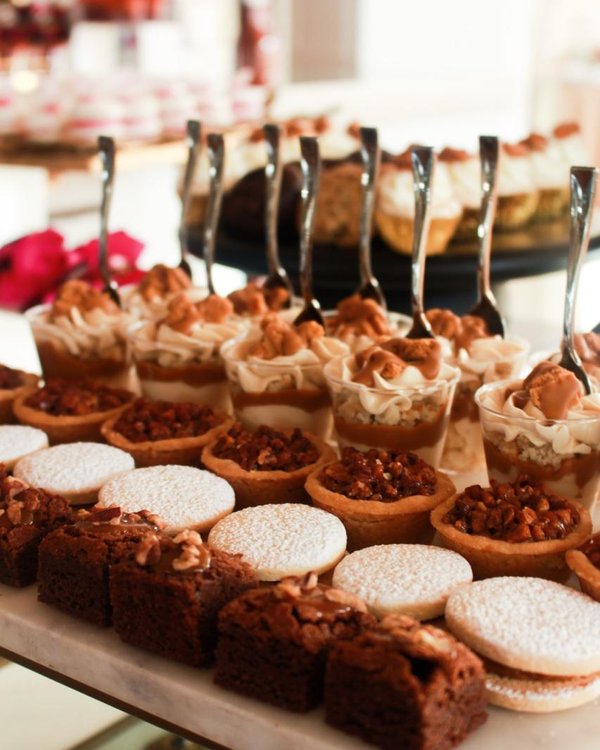 Mesa de postres con pastel de pisos blanco y dorado en salón premium en Monterrey