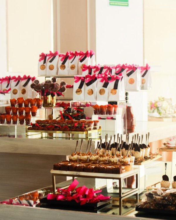 Mesa de postres temática rosa coquette con bolsitas y paletas de chocolate
