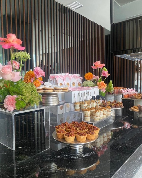 Mesa de postres con rosas amarillas, alfajores y postres individuales